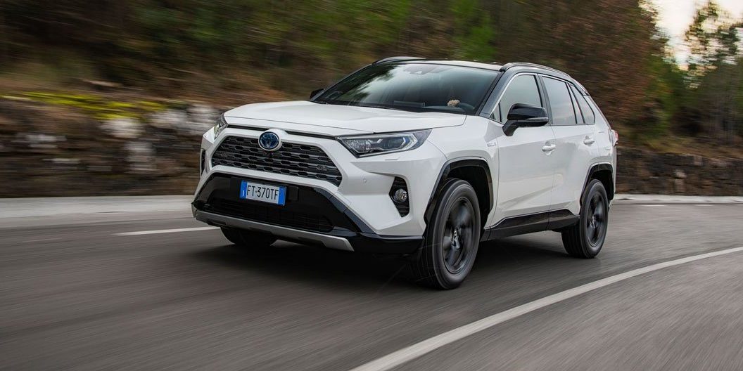 Toyota RAV4 blanche qui roule à toute vitesse sur une route bordée d'arbres
