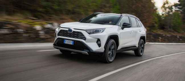 Toyota RAV4 blanche qui roule à toute vitesse sur une route bordée d'arbres