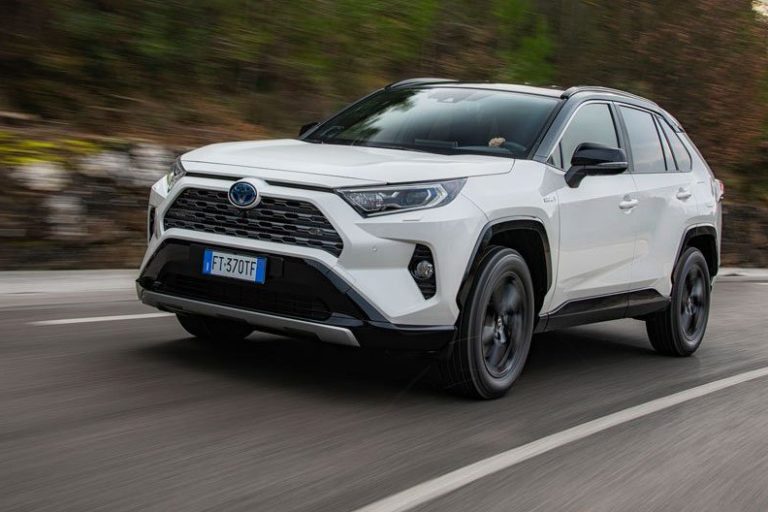 Toyota RAV4 blanche qui roule à toute vitesse sur une route bordée d'arbres
