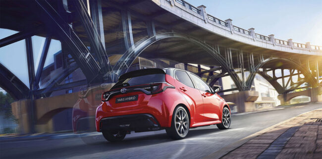 Toyota Yaris rouge roulant sous un pont en ville