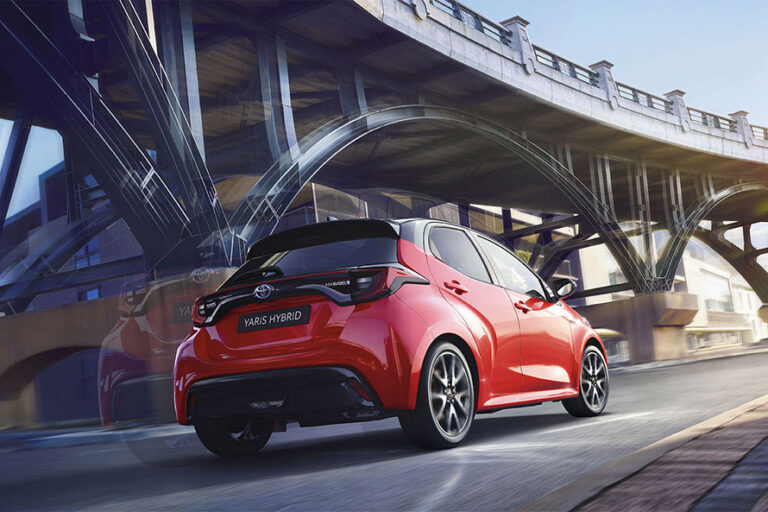 Toyota Yaris rouge roulant sous un pont en ville