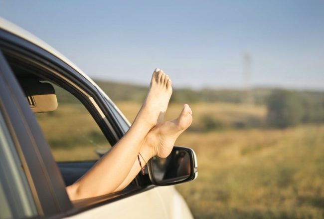 Jambes féminines qui dépassent la fenêtre d'une voiture contrôlée par Gégo Team avant de partir en vacances