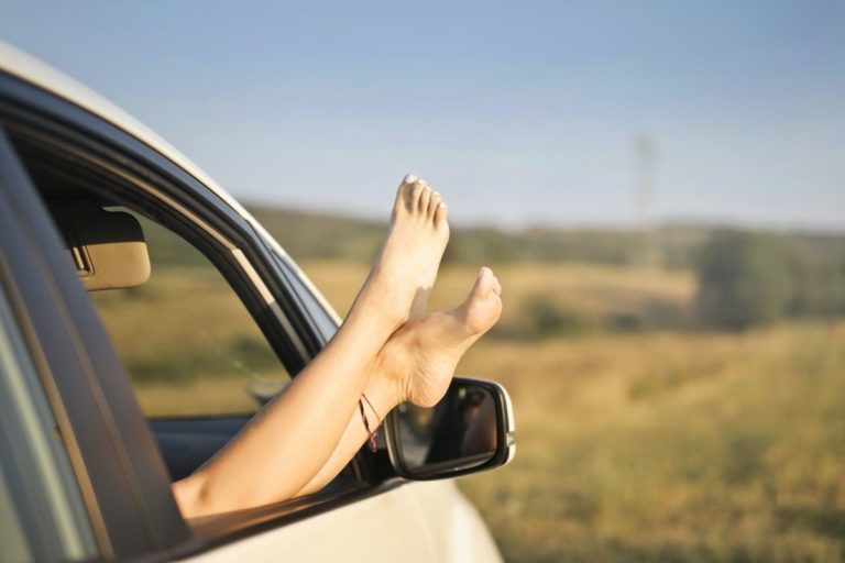 Jambes féminines qui dépassent la fenêtre d'une voiture contrôlée par Gégo Team avant de partir en vacances