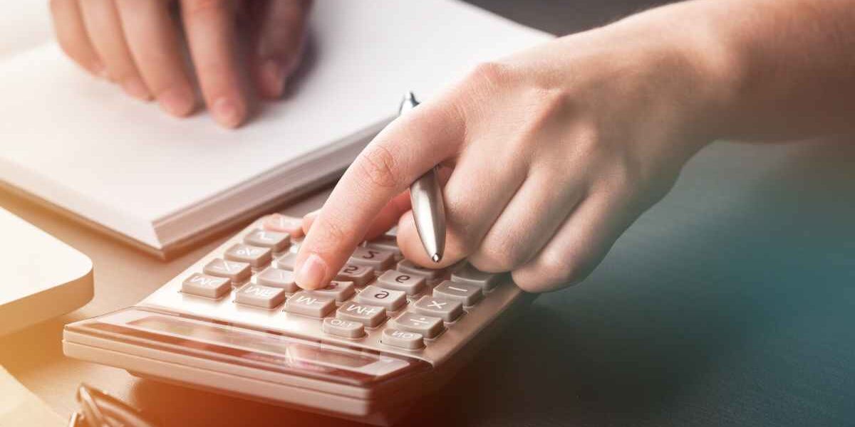 Homme assis à un bureau avec un cahier ouvert et une calculette en train de calculer la fiscalité de sa voiture de société