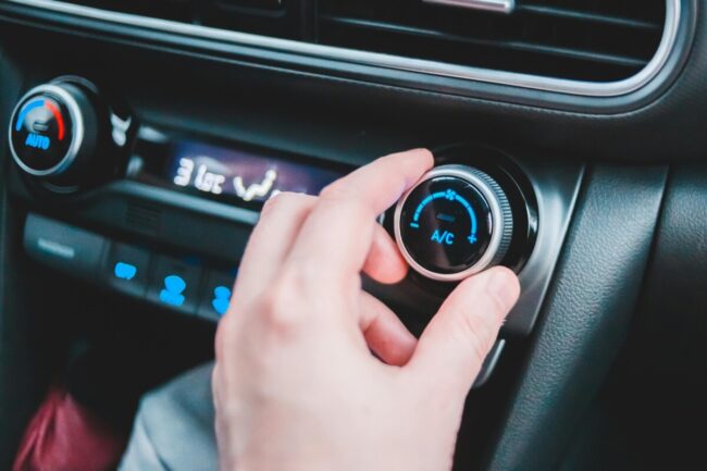 Main d'homme qui règle le bouton de climatisation de sa voiture
